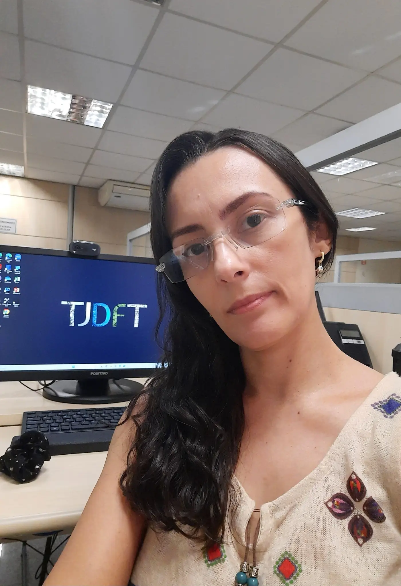 Carolina Kadix em ambiente de trabalho, diante de um computador com a identificação do TJDFT